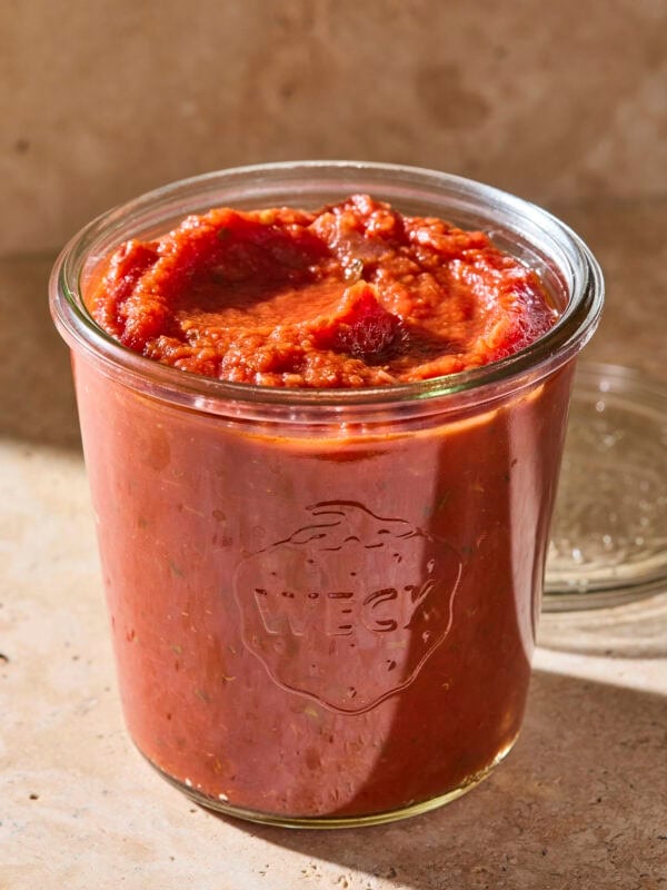 Glass jar filled with red homemade marinara sauce.