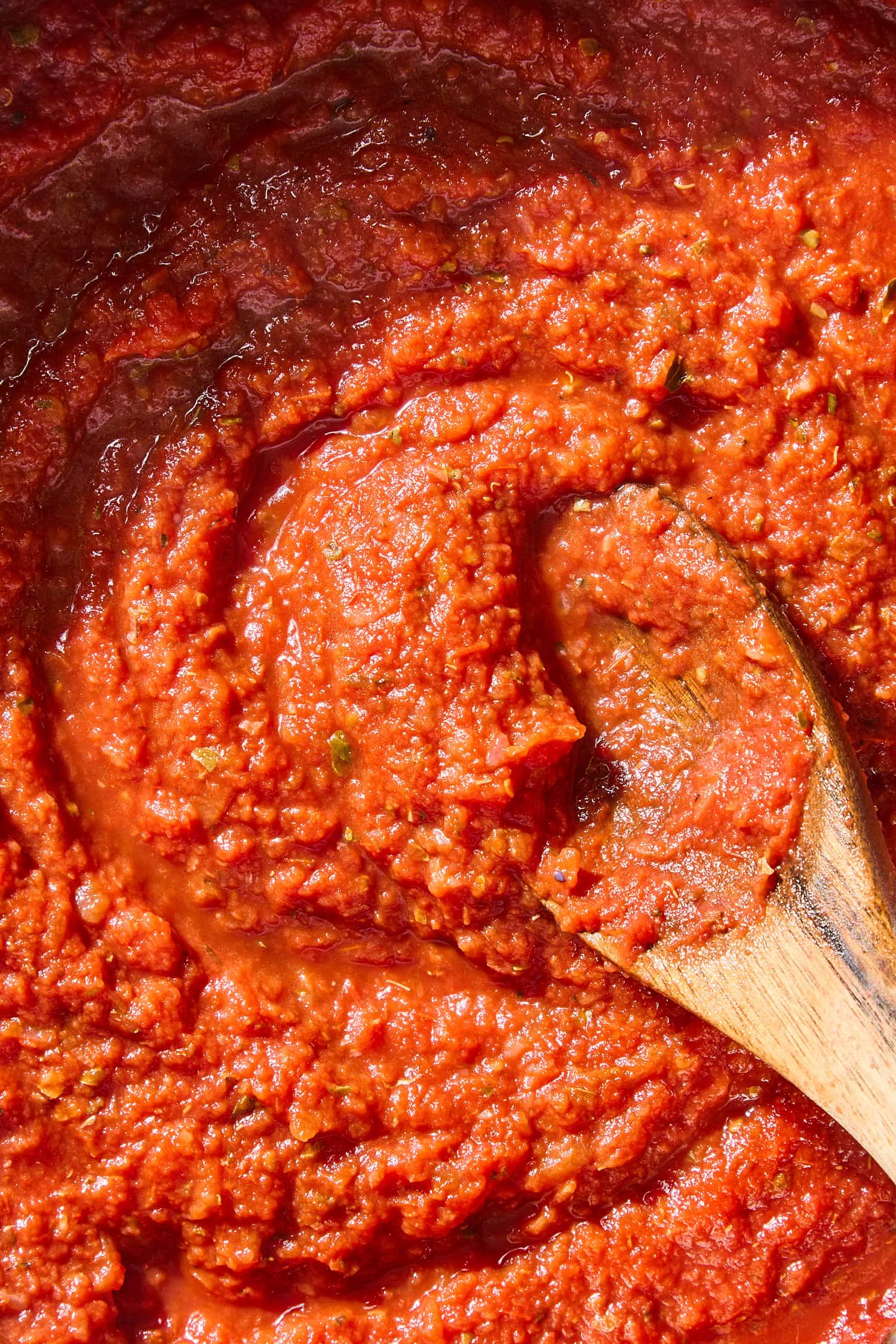 Marinara sauce with spoon resting in saucepan.