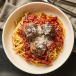 A serving of spaghetti with meatballs on a small plate.