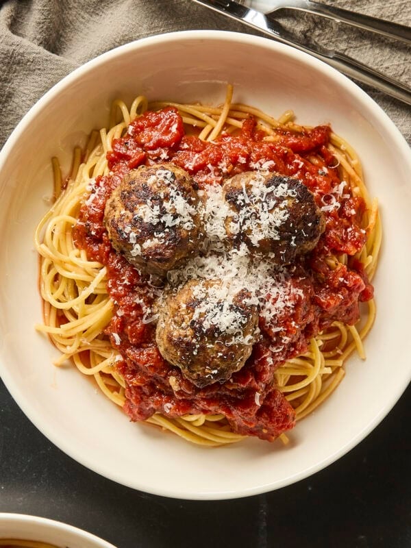 Meatballs and spaghetti plated in a shallow bowl.