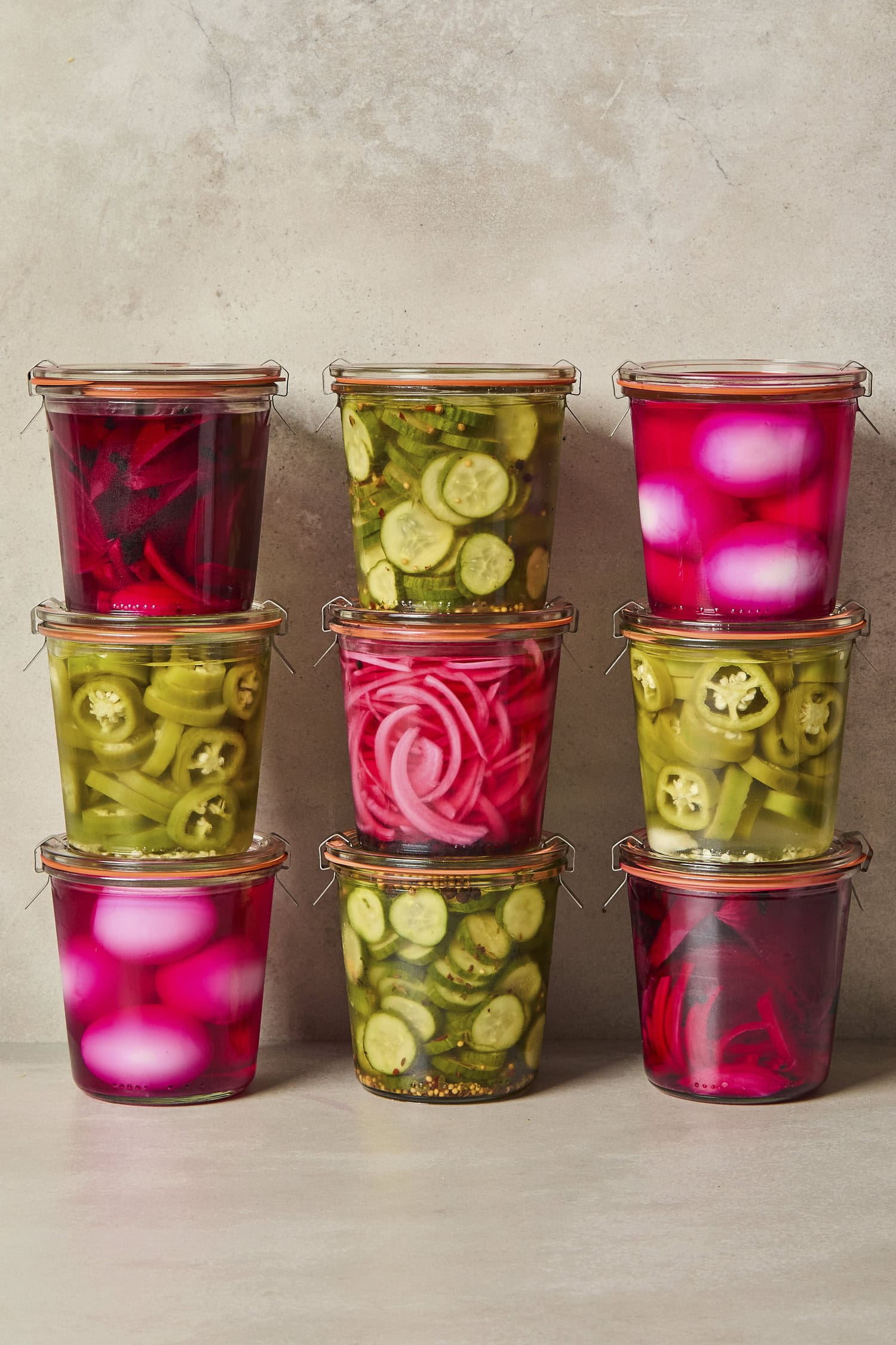 Nine jars of quick pickles on a surface.