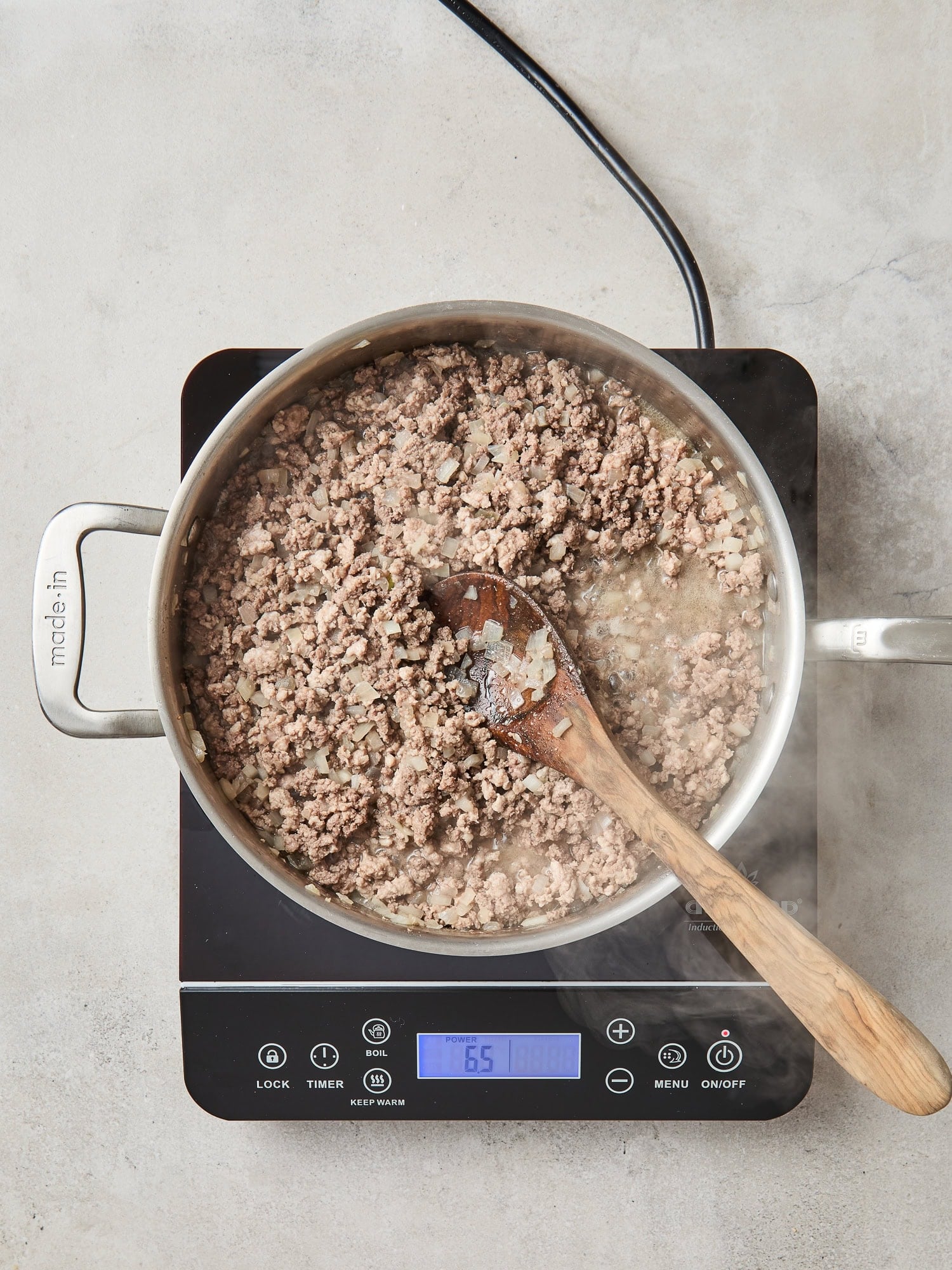 Ground beef and pork cooks in a saucepan over a stovetop.