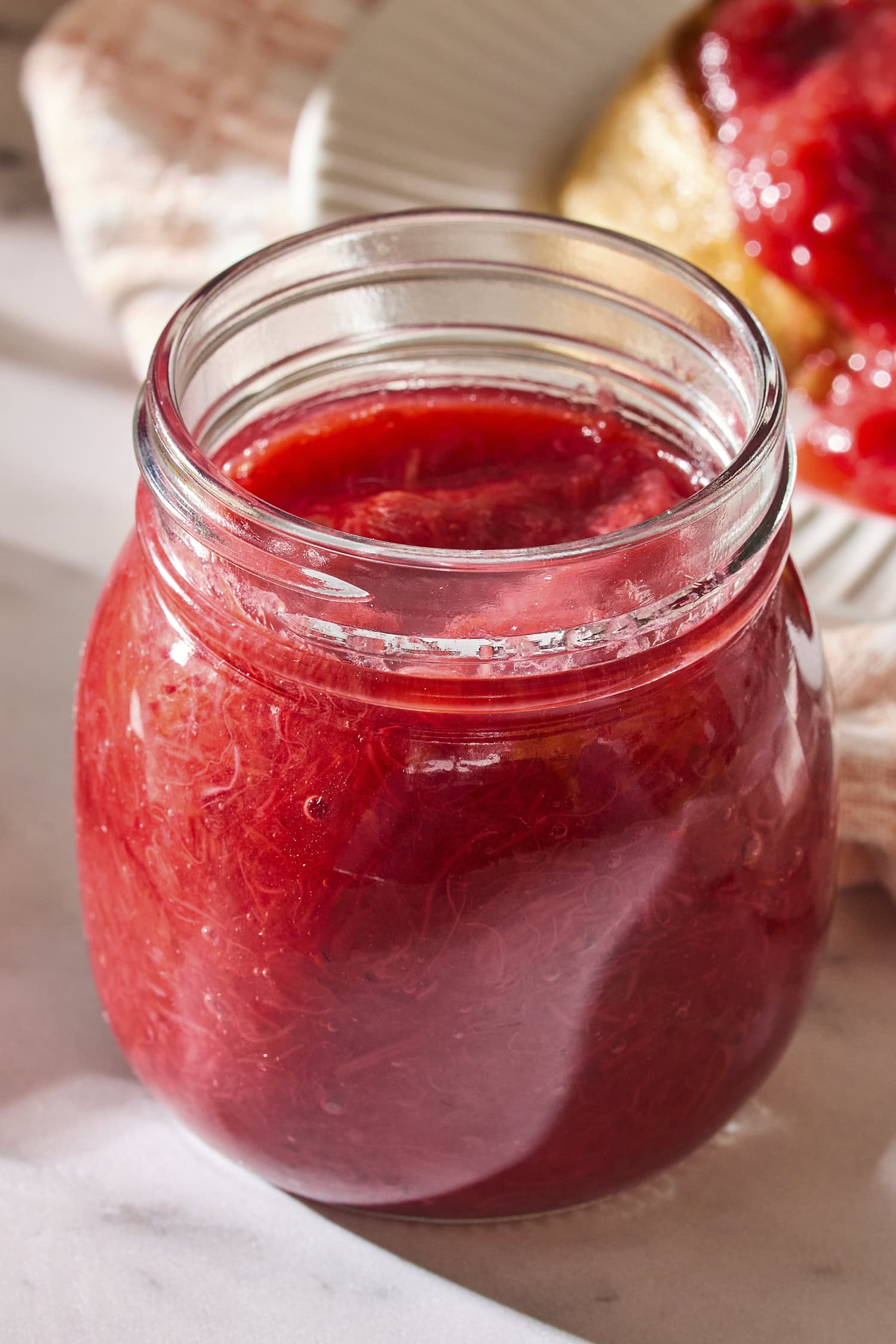 Jar filled with red-colored strawberry rhubarb sauce.