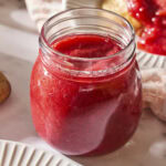Jar of strawberry rhubarb sauce with red color.
