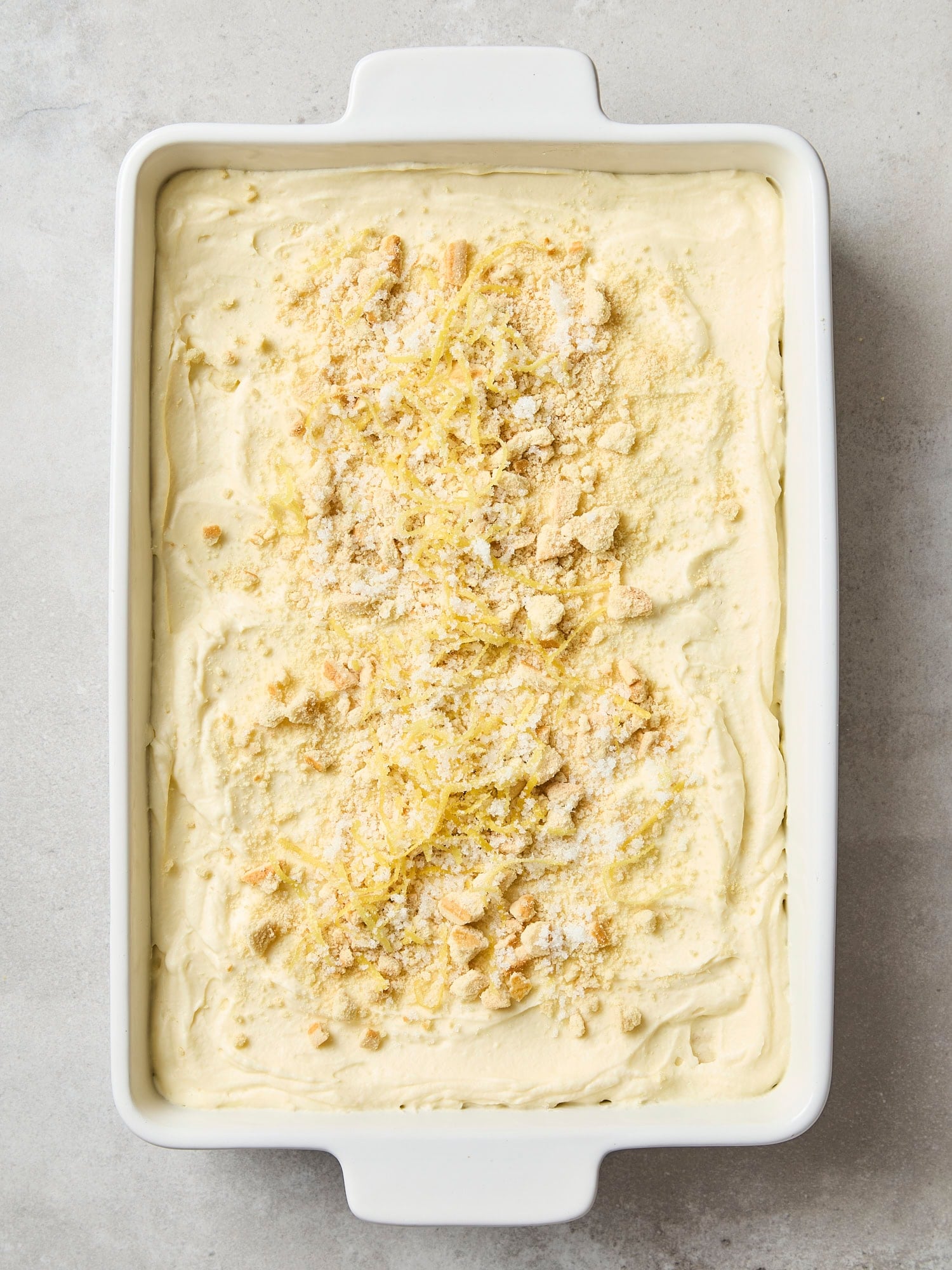 Lemon icebox cake assembled with crushed cookies and lemon zest on top.