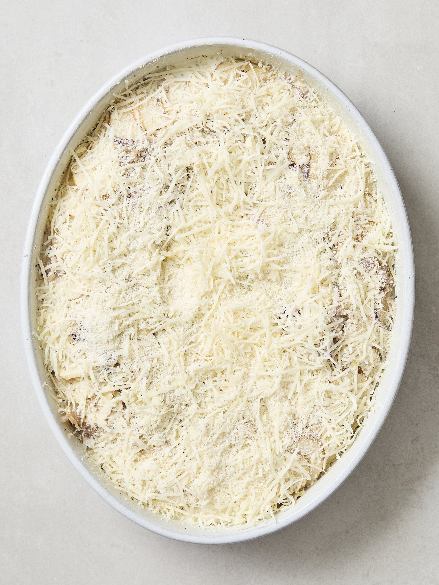Cheese on top of scalloped potatoes in baking dish.