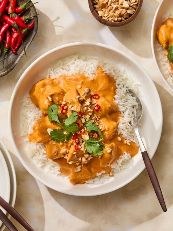 Bowl of butter chicken with chilis and cilantro on top.