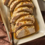 Slices of pork roast on a platter with glaze on top.