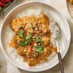 Bowl with butter chicken spooned on top of rice.