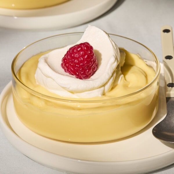 Glass filled with homemade lemon pudding with whipped cream on top.