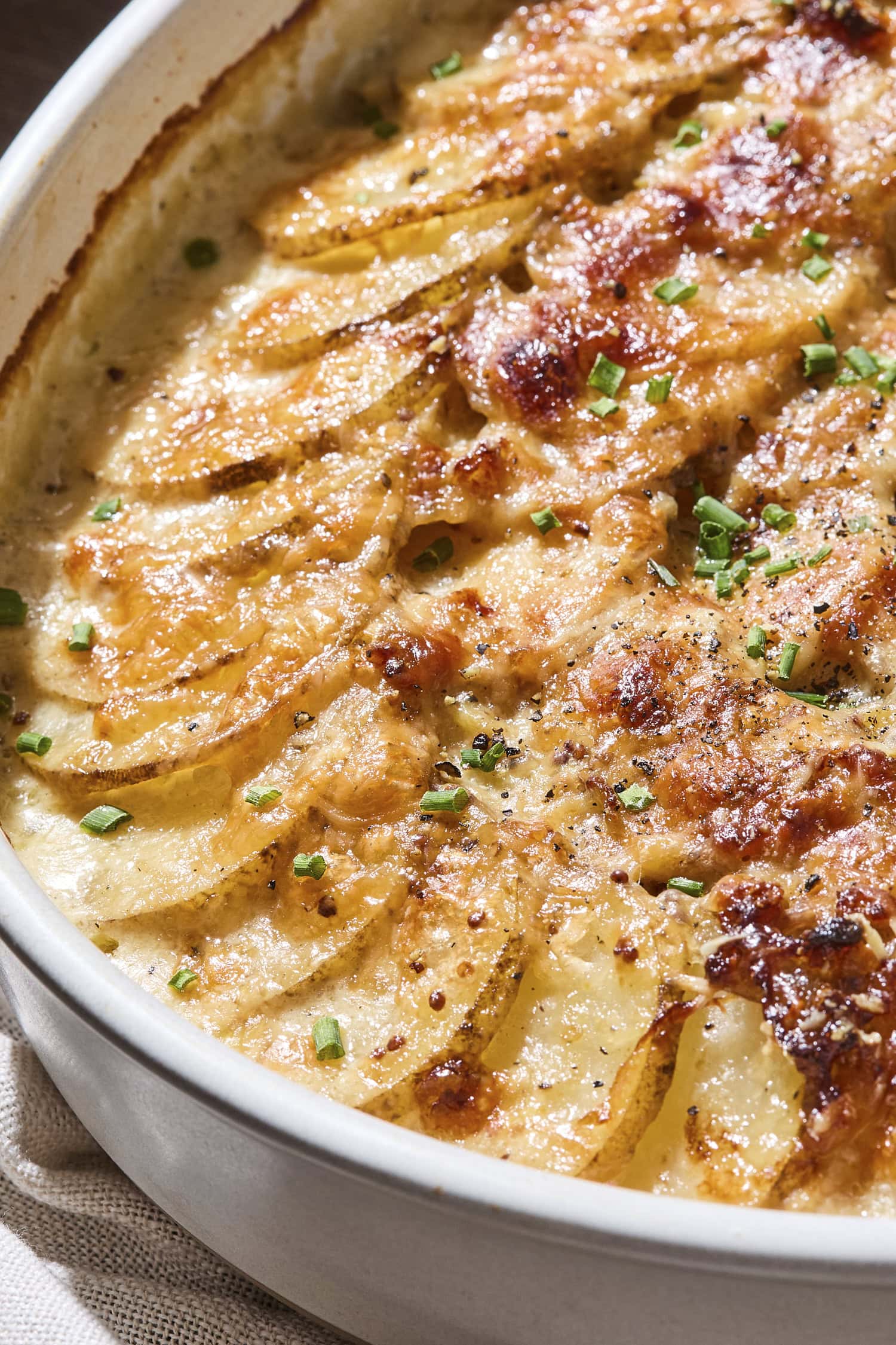 Shingled scalloped potatoes topped with chives.