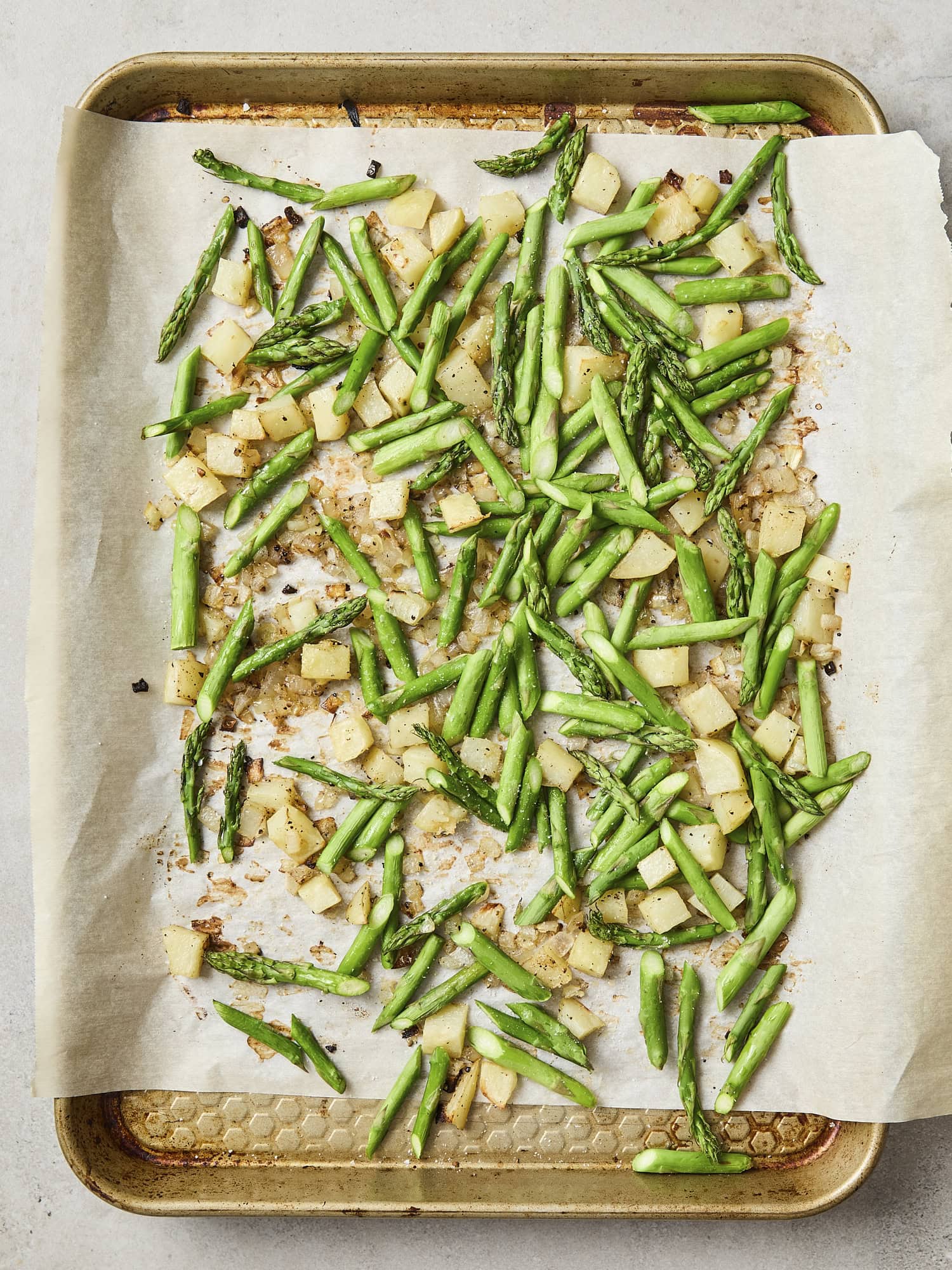 Mixture of roasted asparagus, onion, and potatoes on sheet pan.