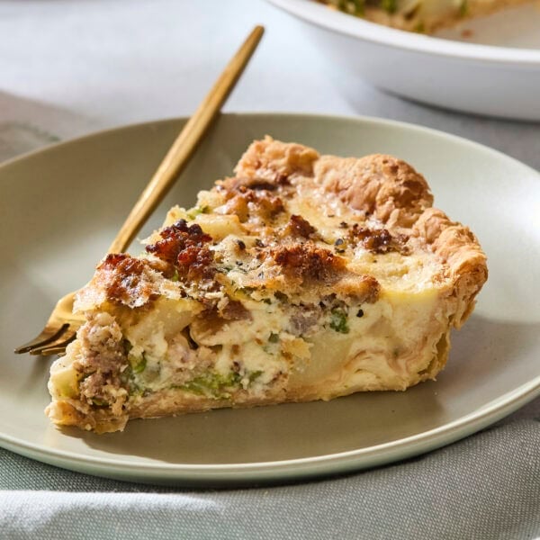 Slice of sausage asparagus quiche with fork.