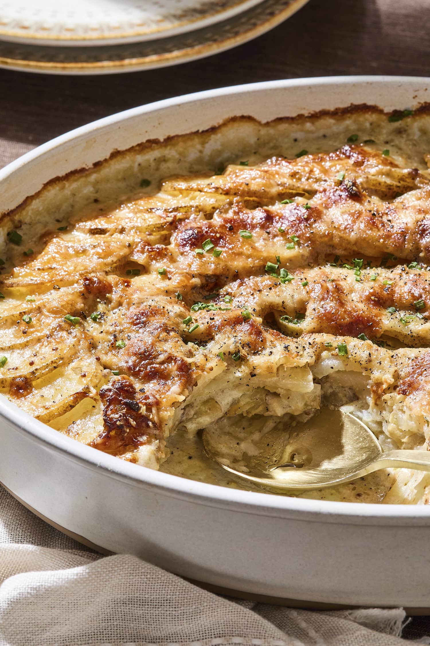 Scoop taken out of baking dish with scalloped potatoes.