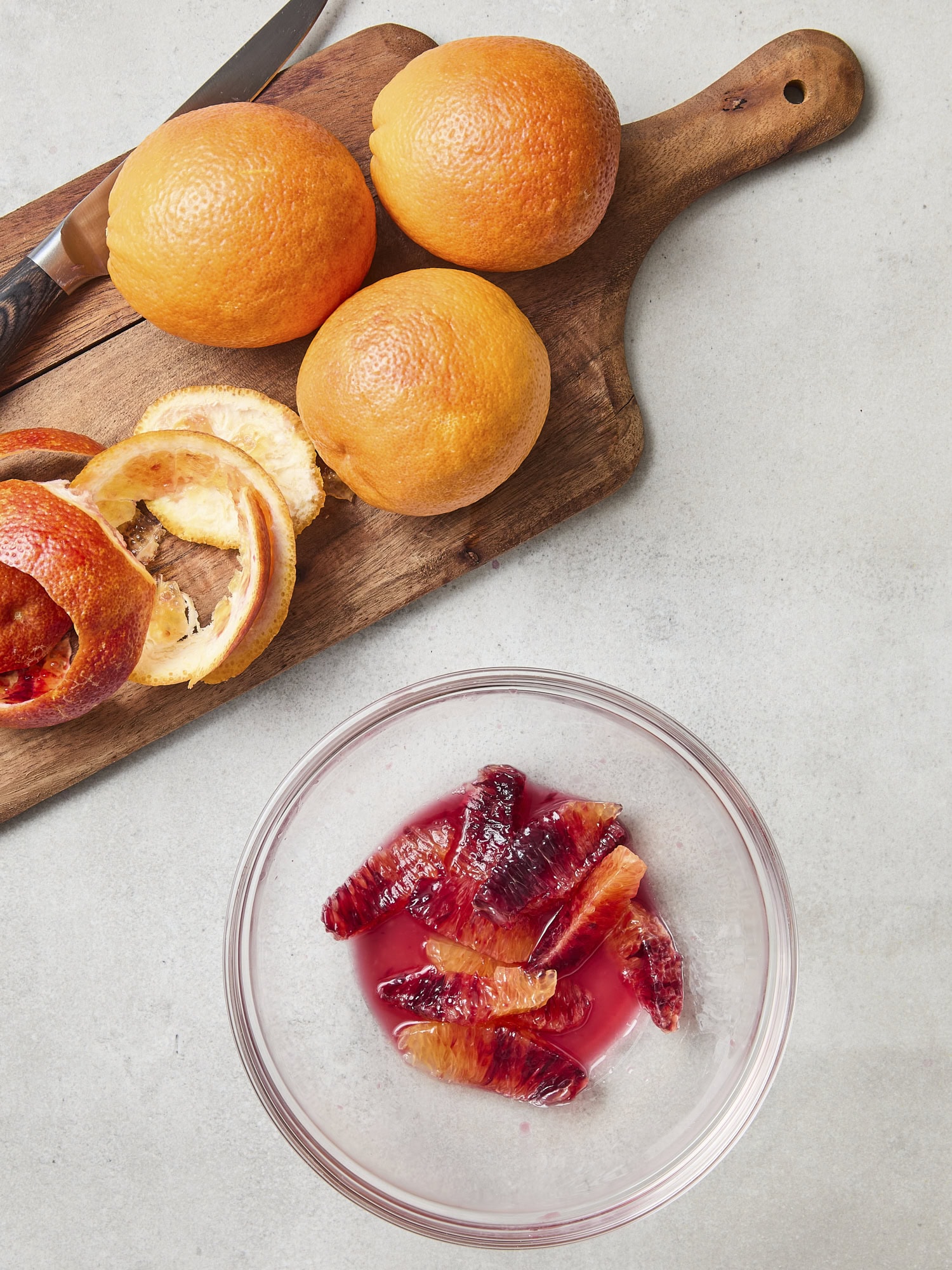 Blood oranges being segmented into a bowl.