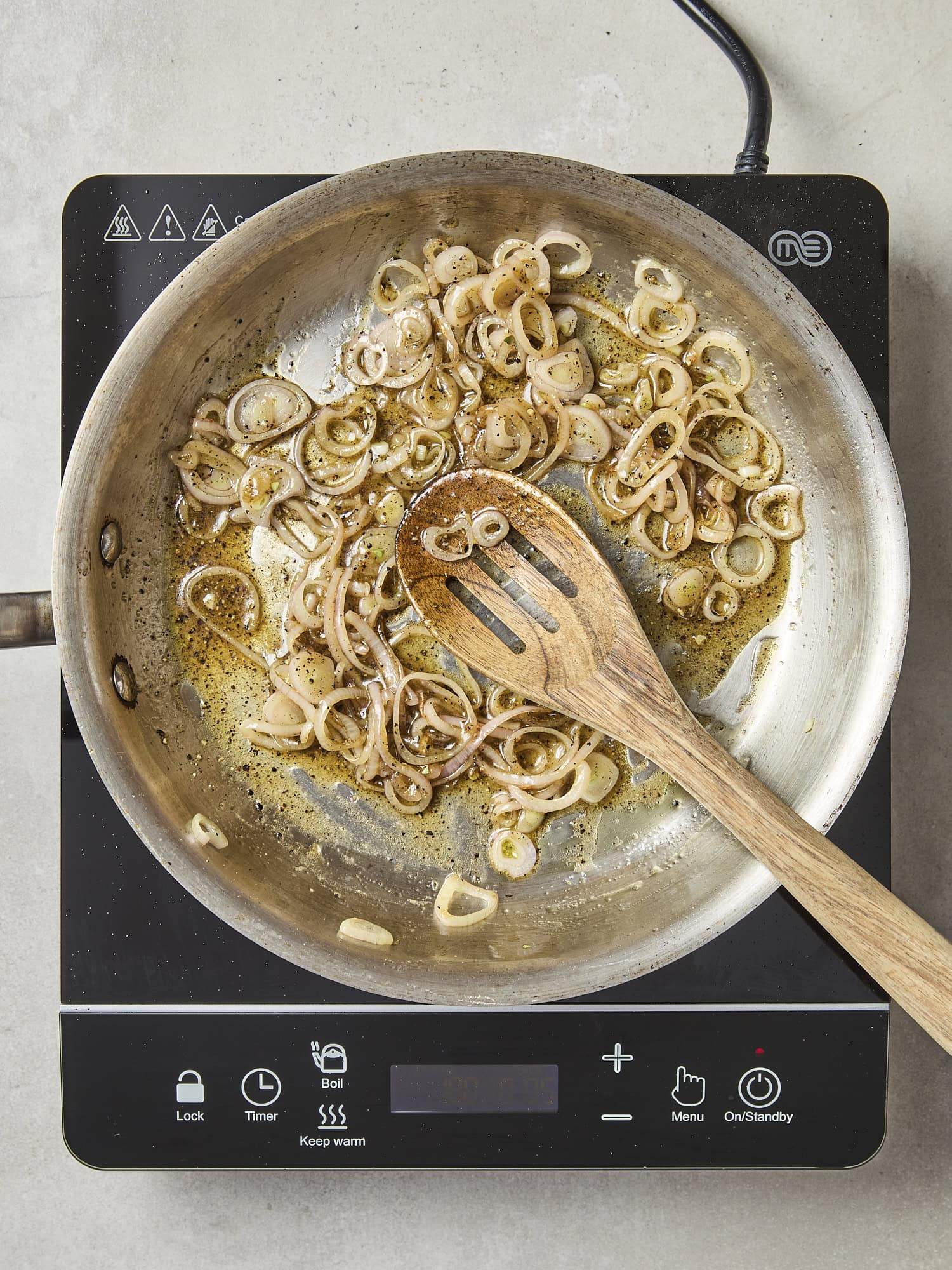 Sliced browned shallot in skillet with vinaigrette created.