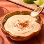 Wood bowl with chipotle mayo with spoon holding some.