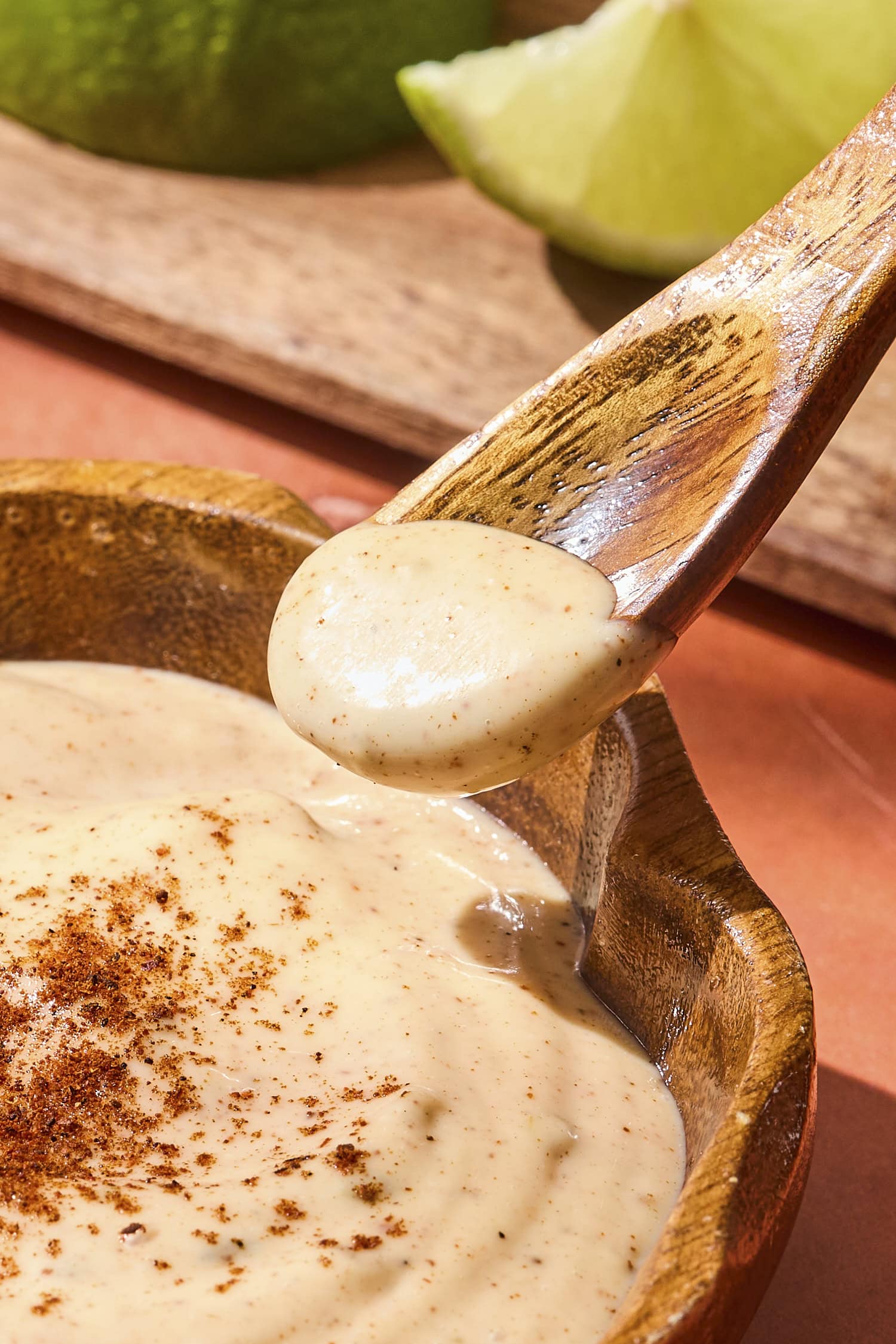 Spoon holding light orange chipotle mayo sauce.