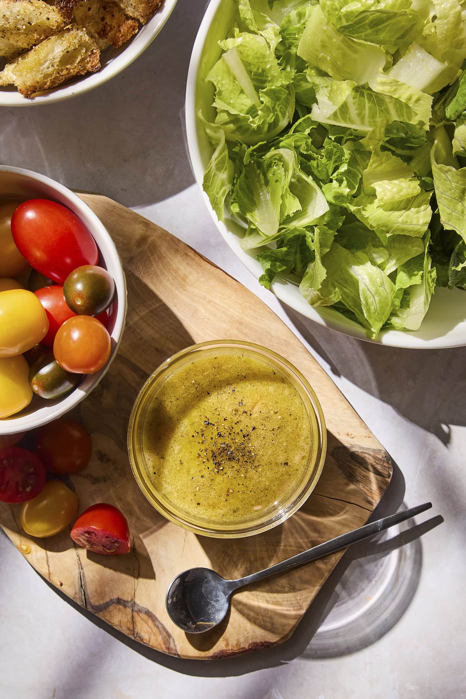 Glass jar filled with creamy Dijon vinaigrette with lettuce and cherry tomatoes.