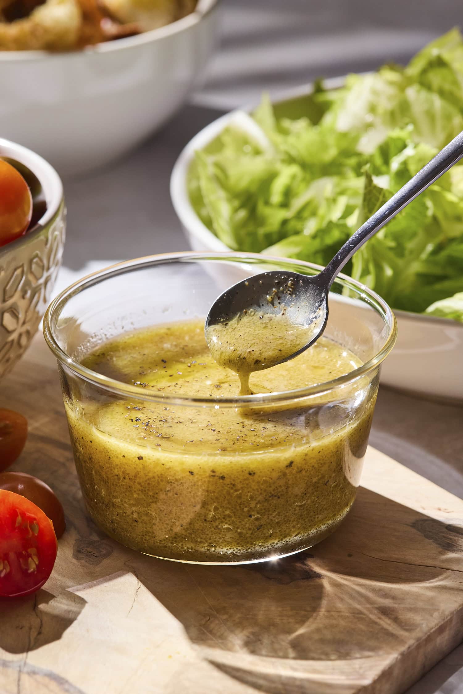 Spoon scooping up Dijon vinaigrette from glass jar.