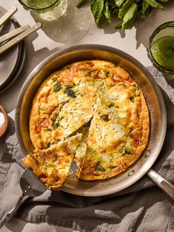 Removing a wedge of tomato spinach frittata from the pan.