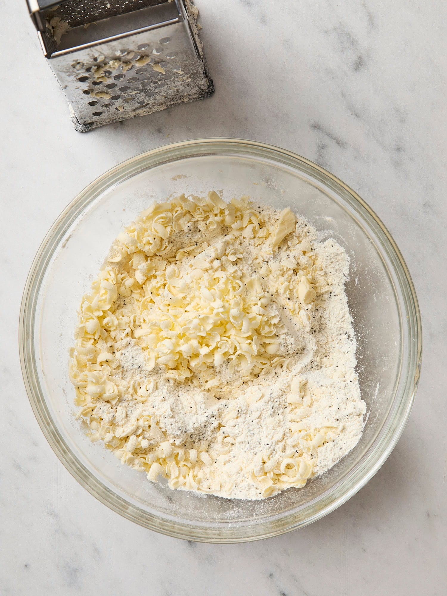 Grated butter with dry ingredients for lemon poppy seed scones.