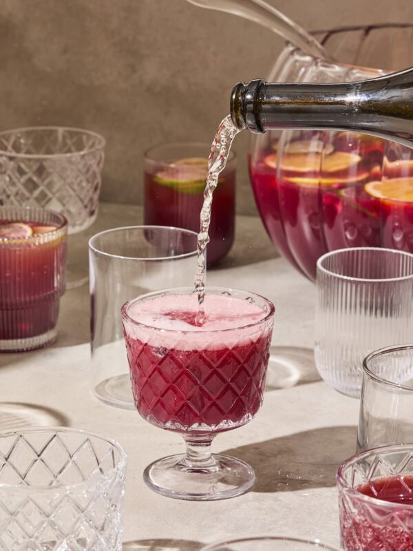 Champagne pouring on top of pomegranate punch.