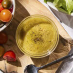 Glass bowl filled with Dijon vinaigrette dressing for salad.