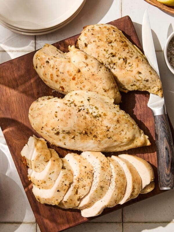 Sliced and unsliced baked chicken breast on cutting board.
