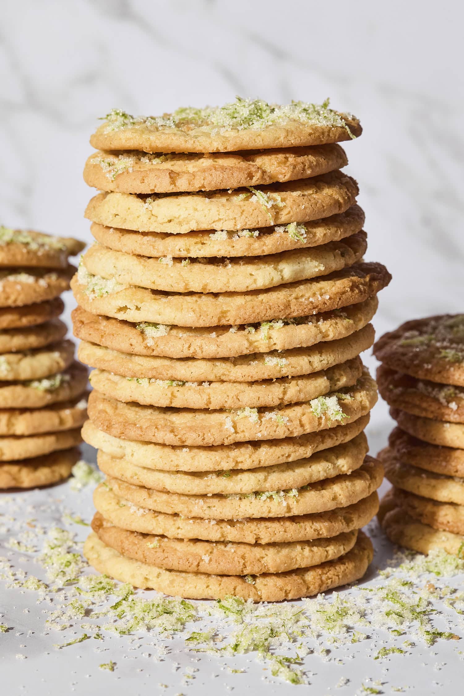 Stack of lime sugar cookies with more zest sprinkled.