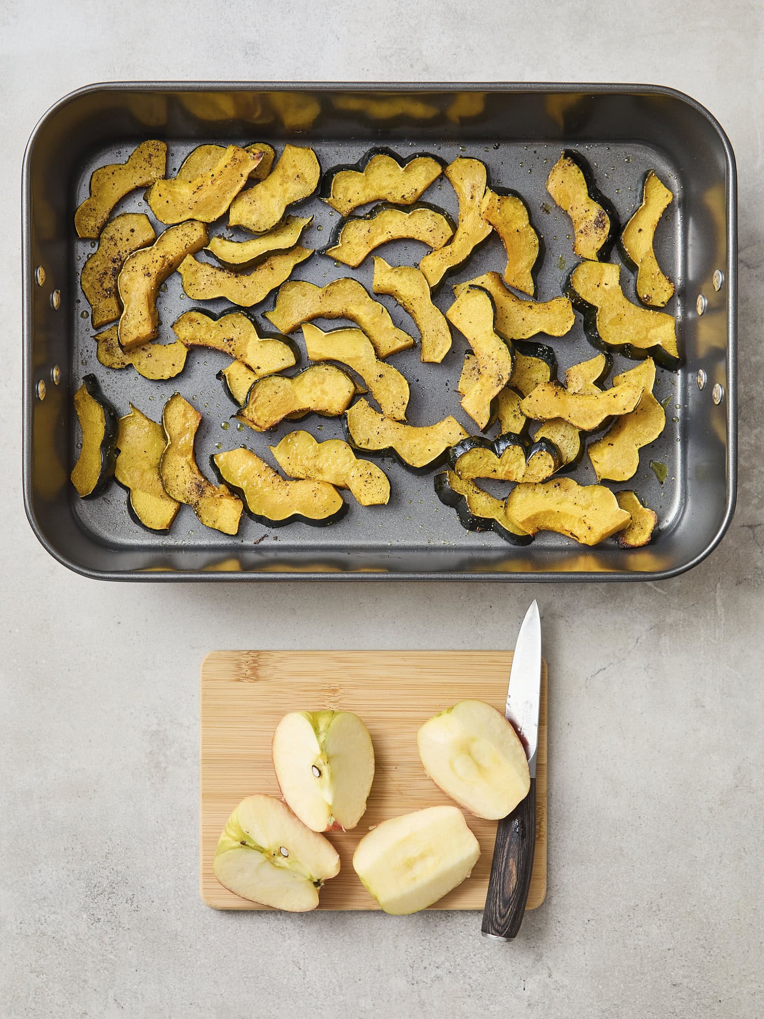 Apples being sliced before being added to baking pan with squash.