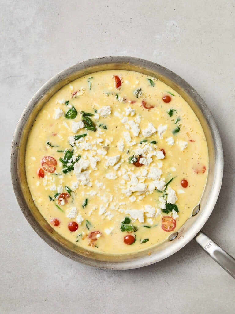 Egg mixture topped with feta cheese before baking in the oven.