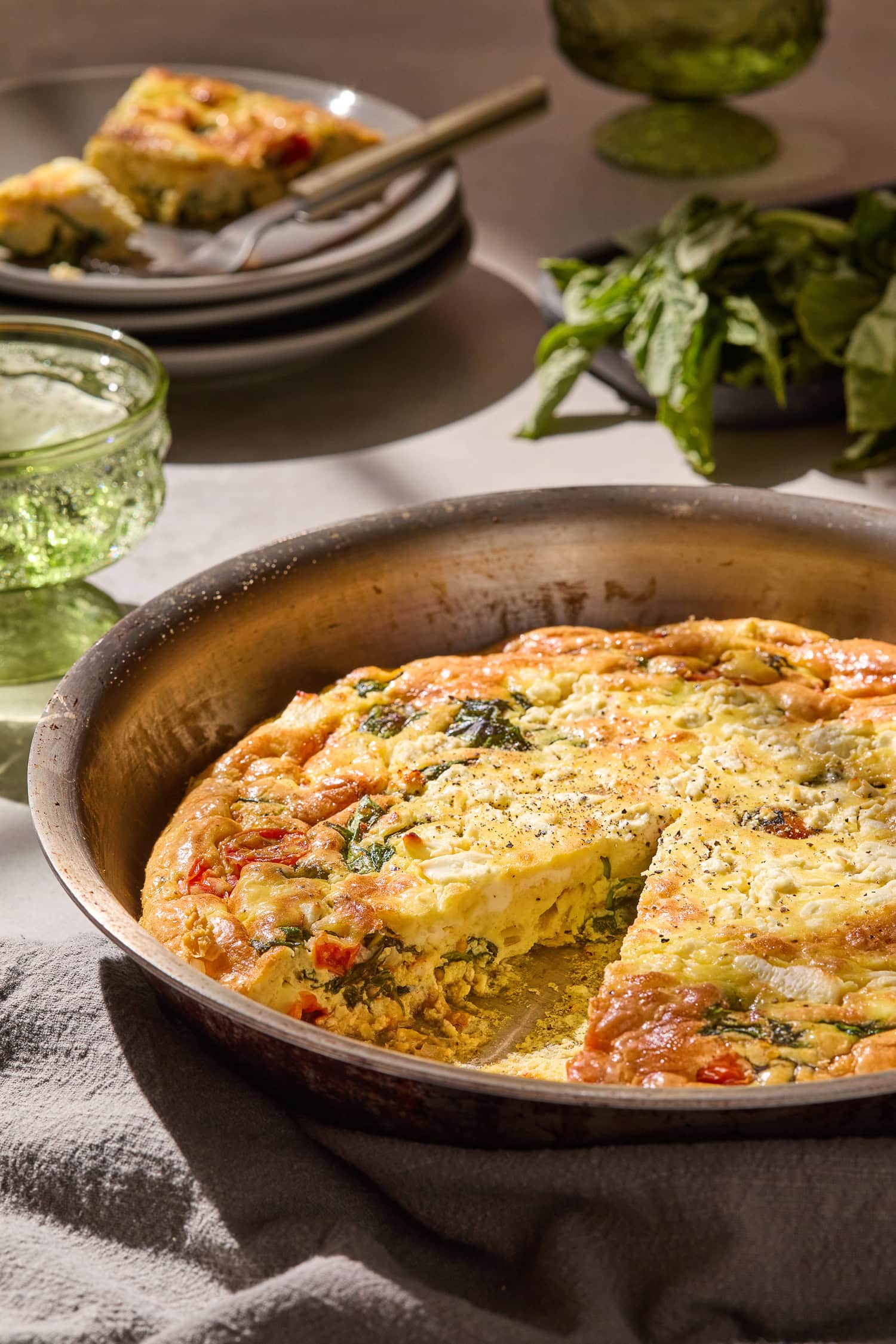 Sliced tomato and spinach frittata in a skillet.