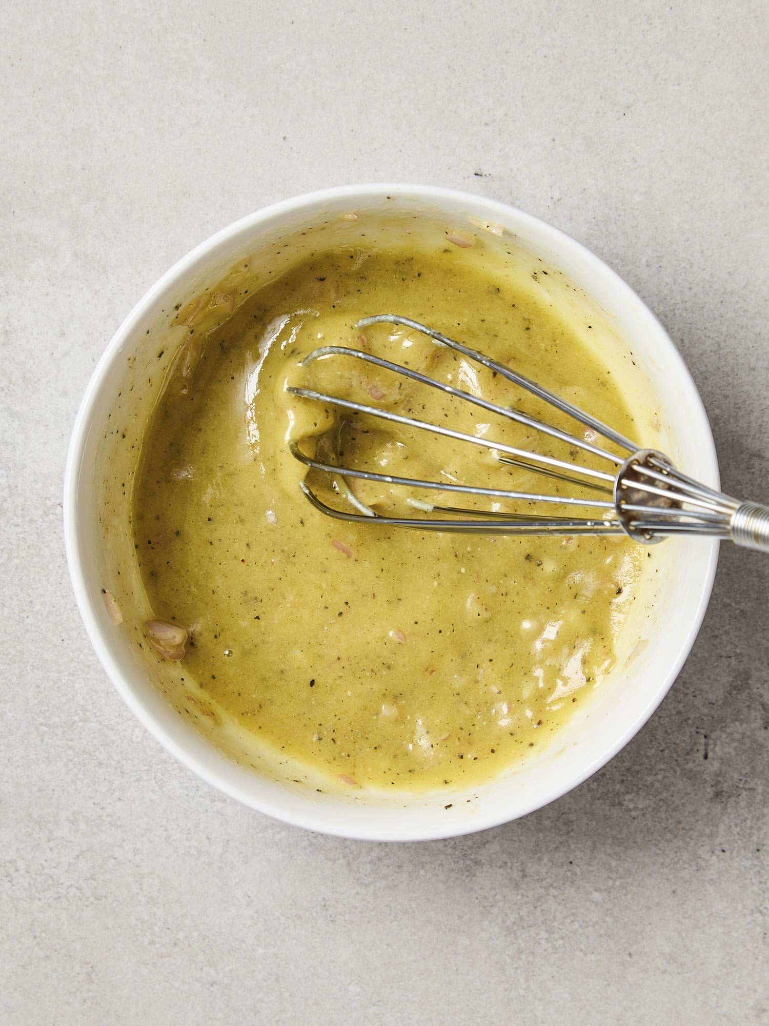 Whisking a Dijon vinaigrette with small bowl.
