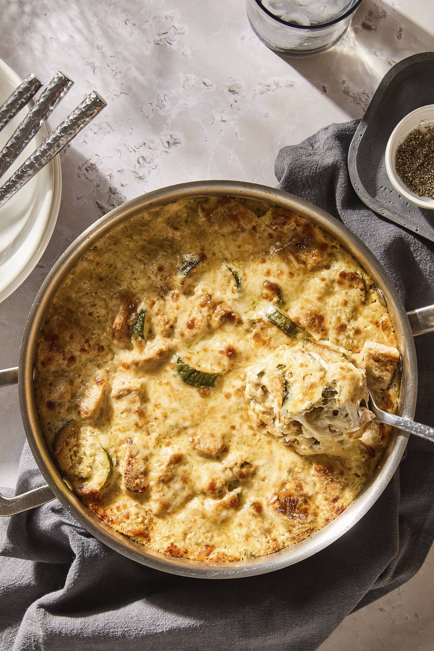Spoon scooping out cheesy chicken casserole with zucchini.