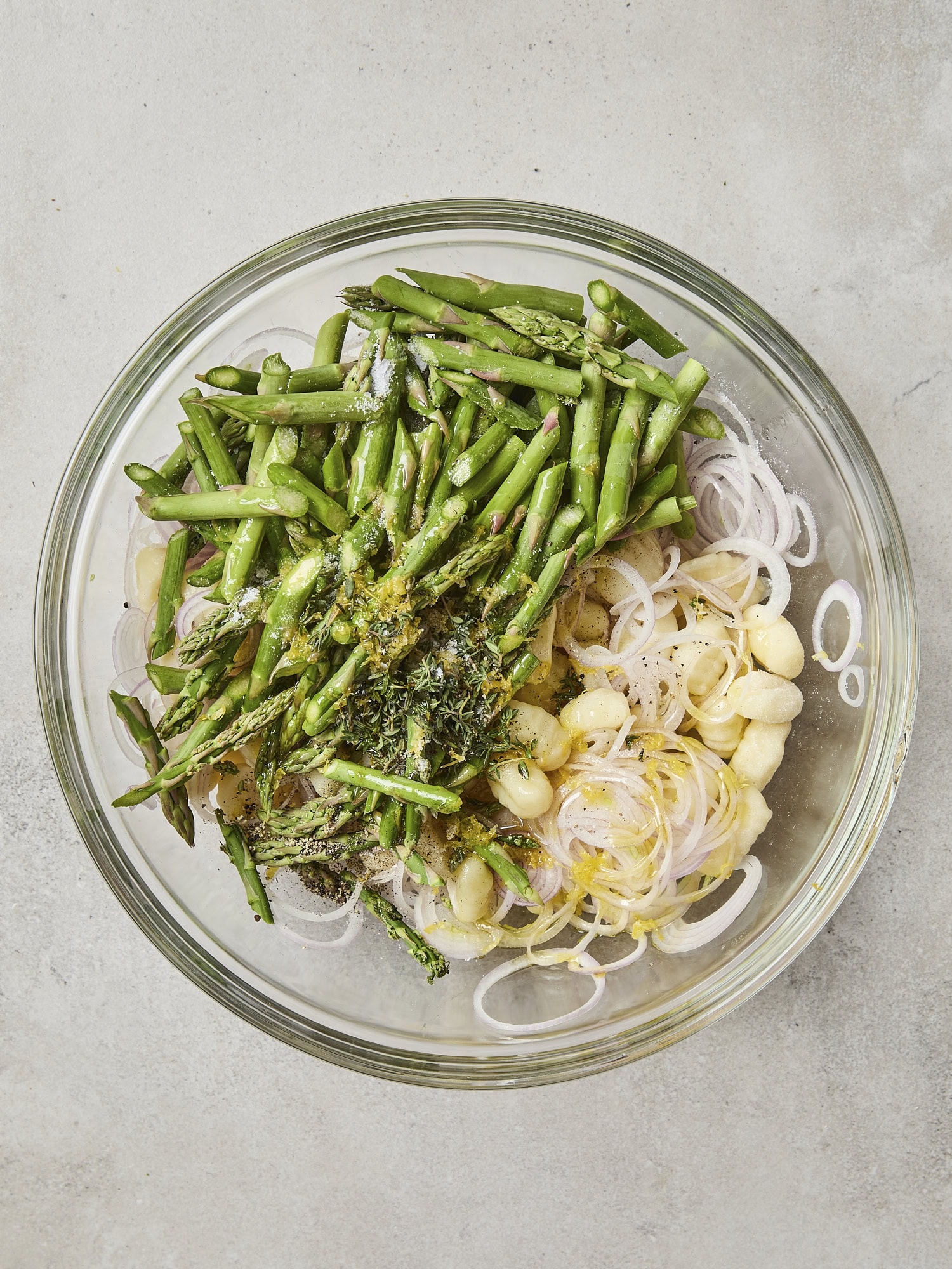 Glass bowl with gnocchi, shallot, and asparagus.
