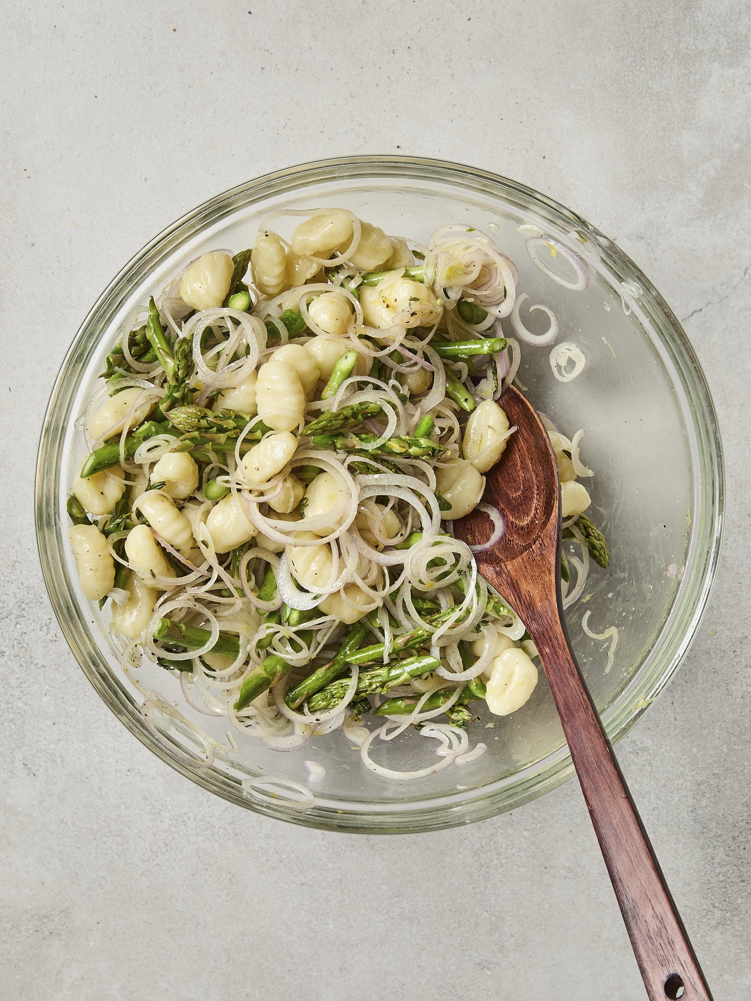 Glass bowl with mixture of gnocchi with vegetables.