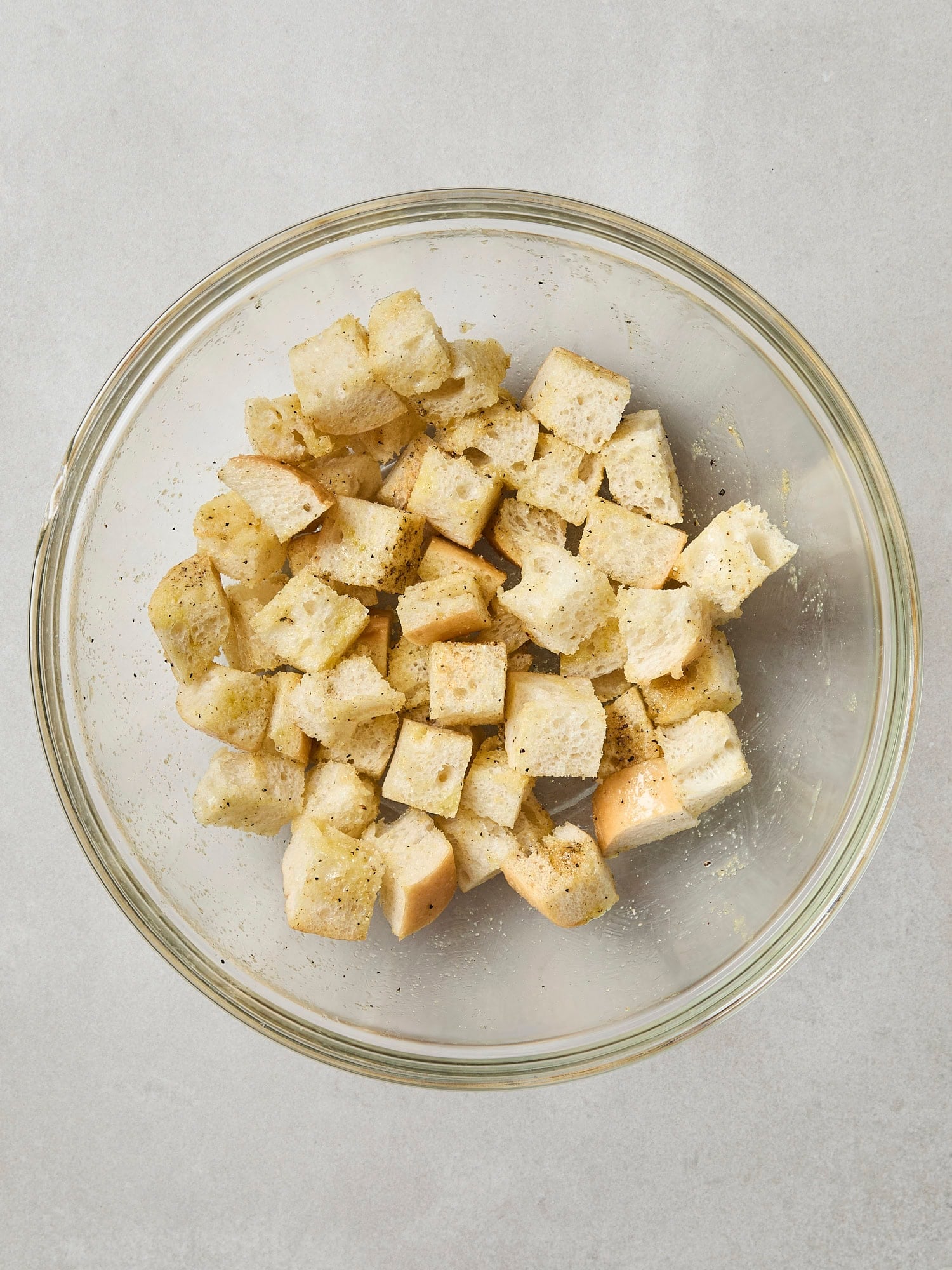 Glass bowl with cubed bread seasoned for croutons.