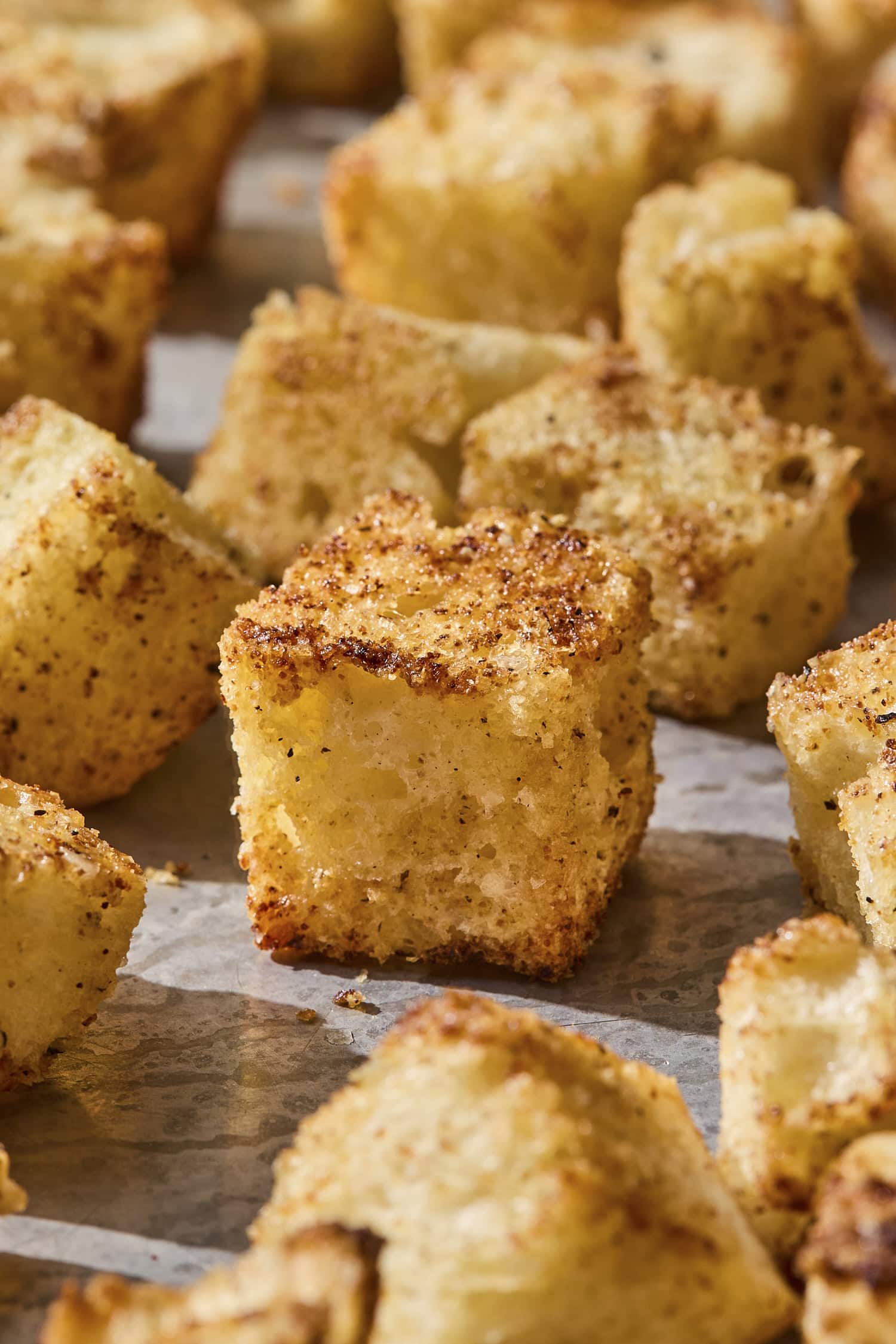 Baked crispy and golden homemade croutons on a sheet pan.
