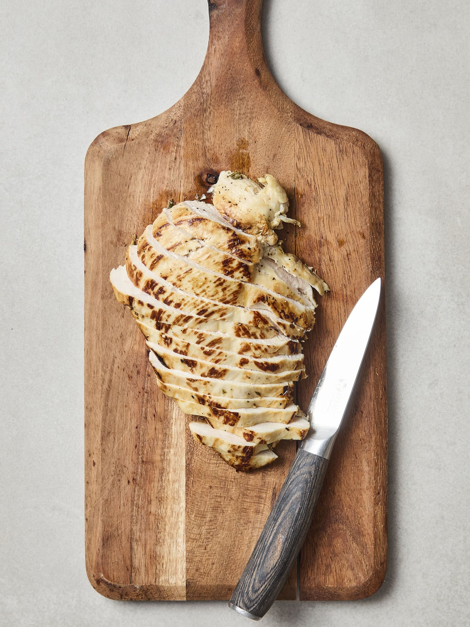 Slicing chicken breast on cutting board.
