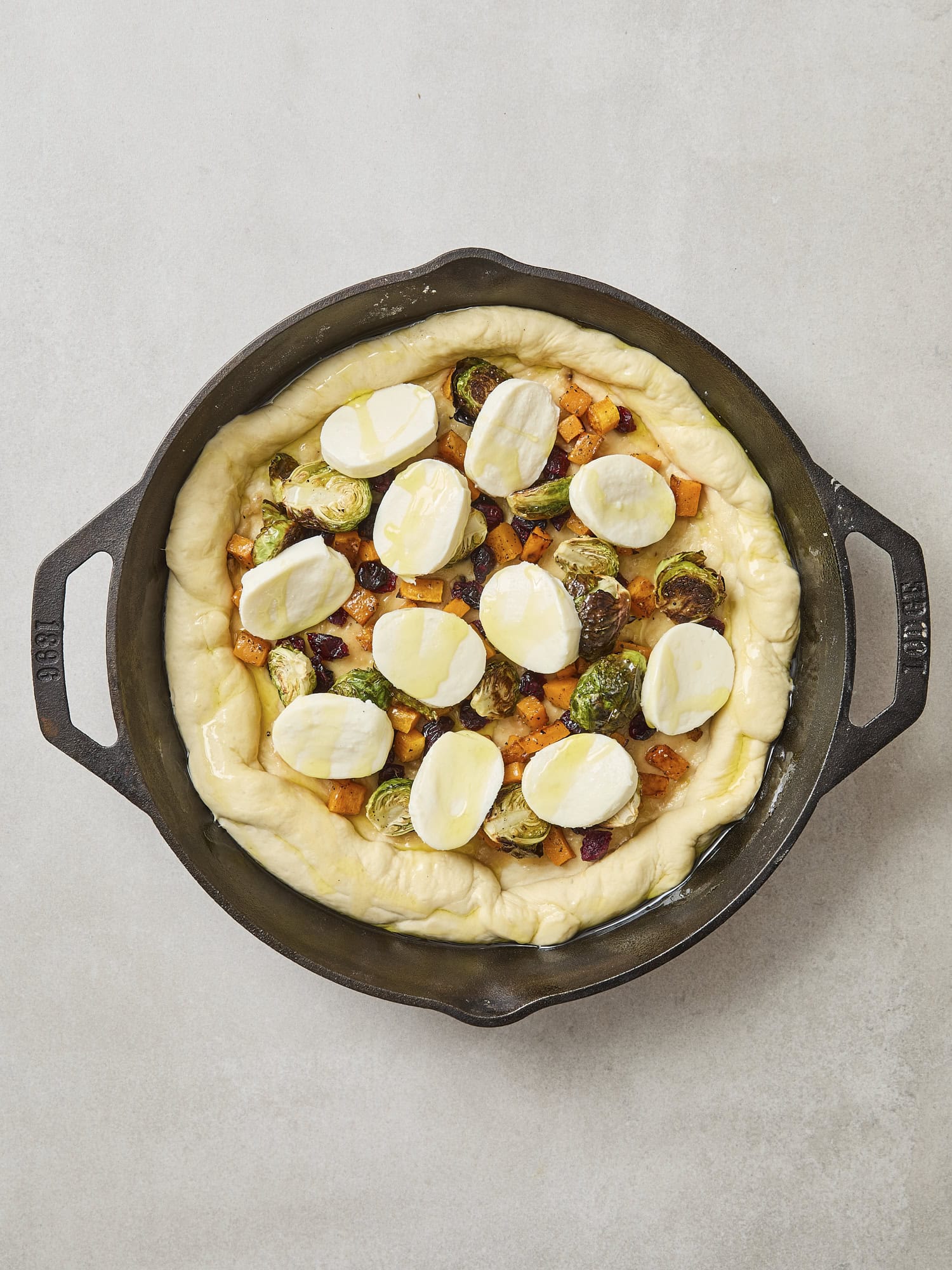 Unbaked pizza with slices of mozzarella on top.