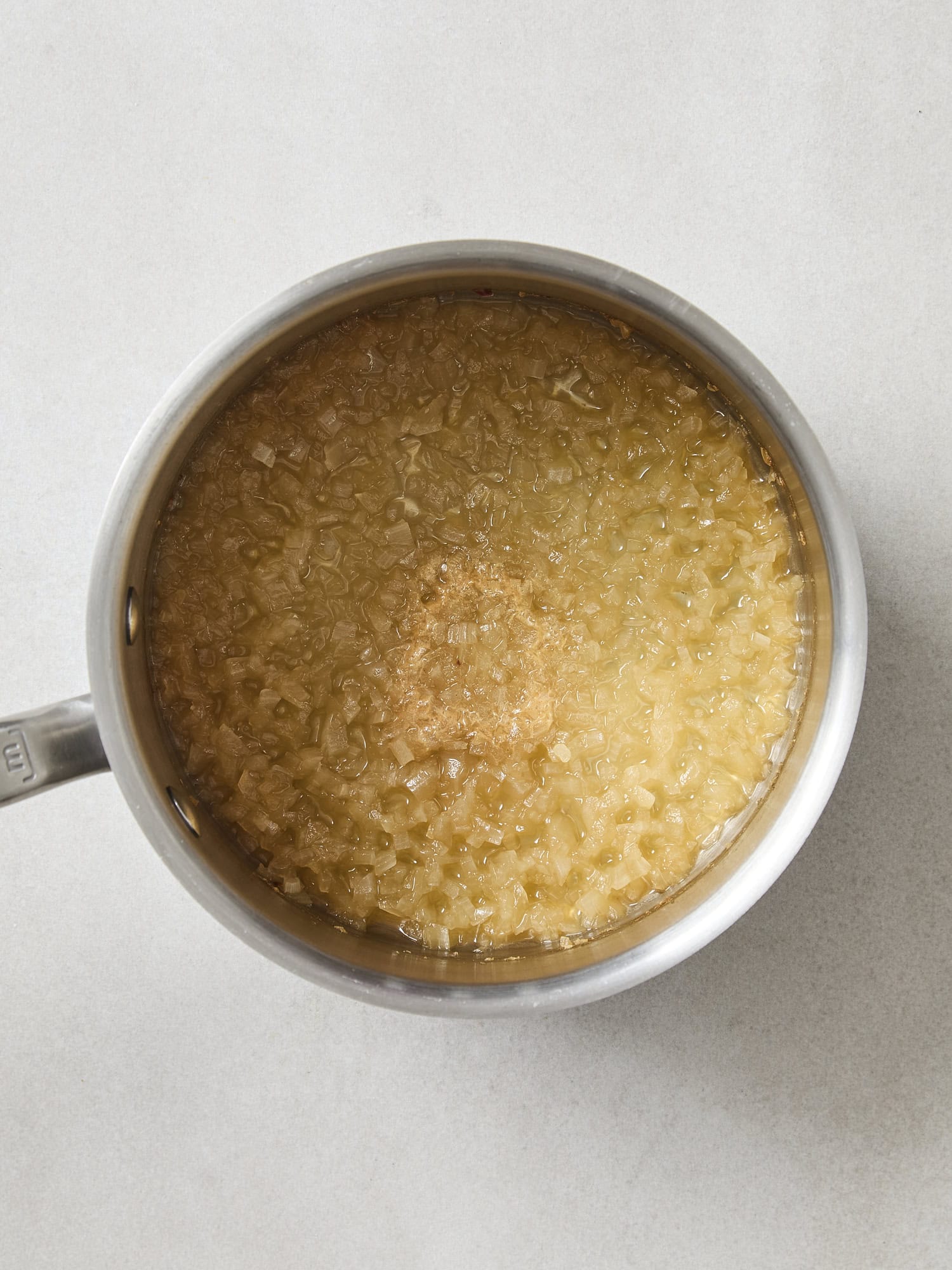 Saucepan with reduced onion and apple cider mixture.