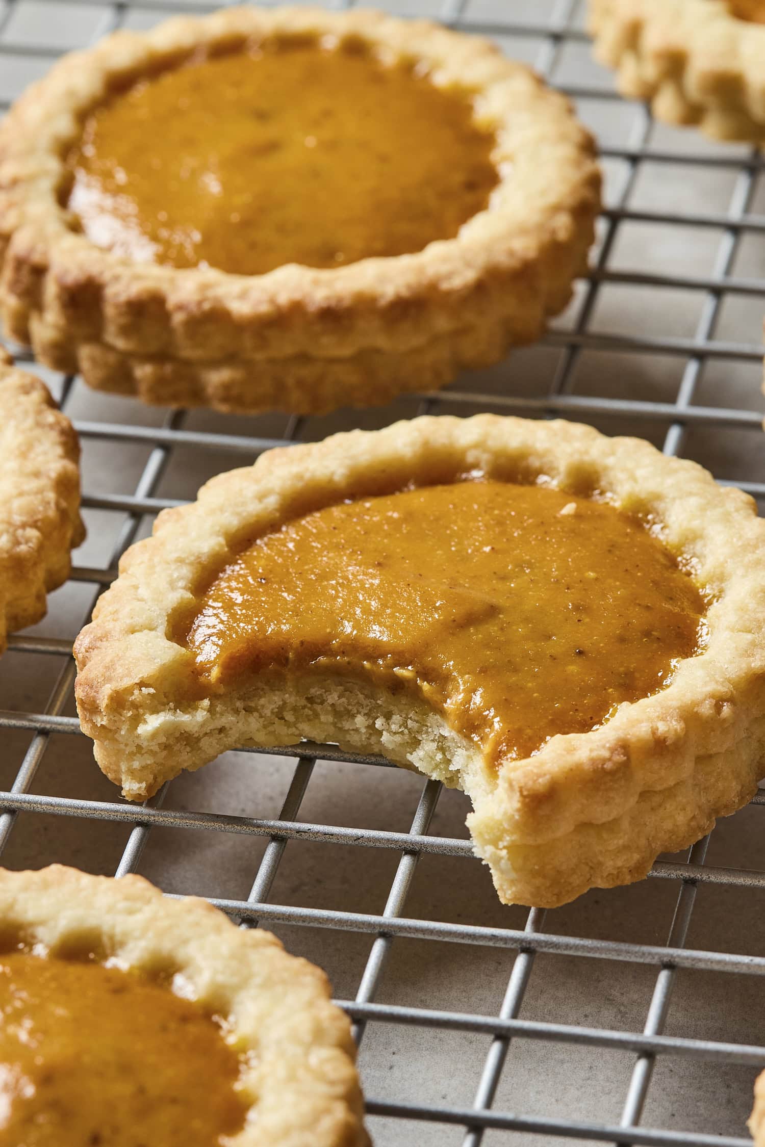 Bite taken out of pumpkin pie cookie on cooling rack.