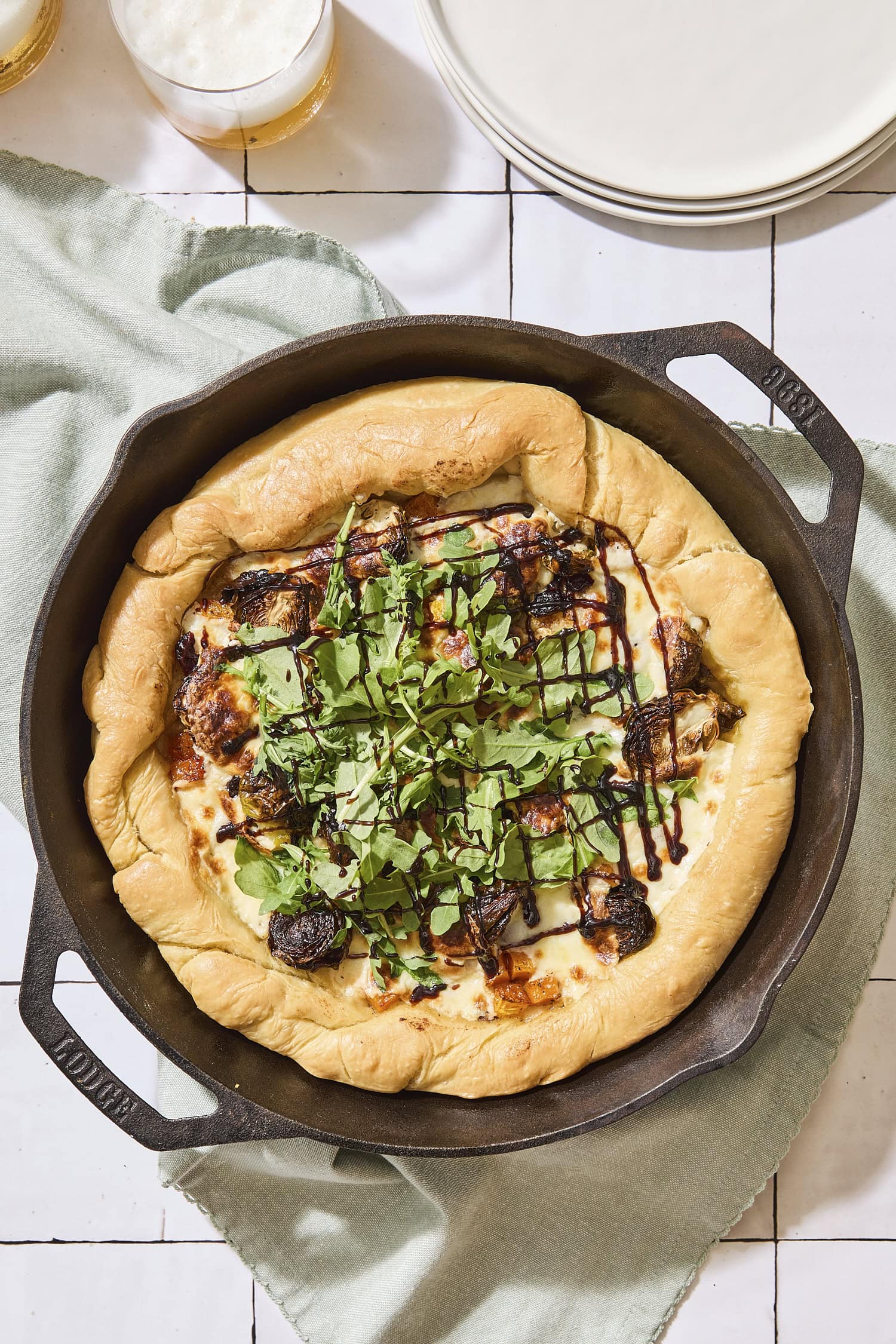 Baked butternut squash pizza in skillet topped with arugula.