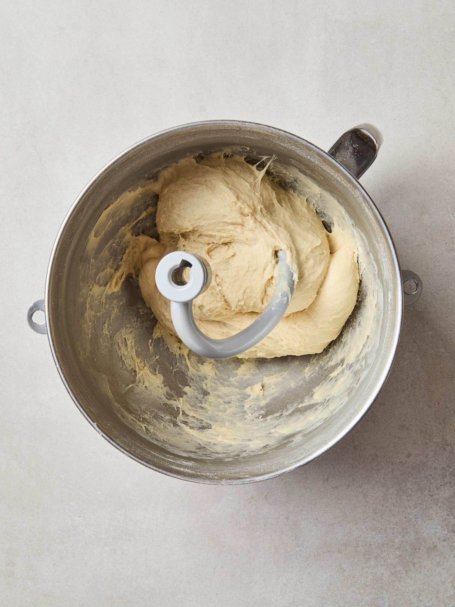 Dough for cinnamon rolls being kneaded in a stand mixer.