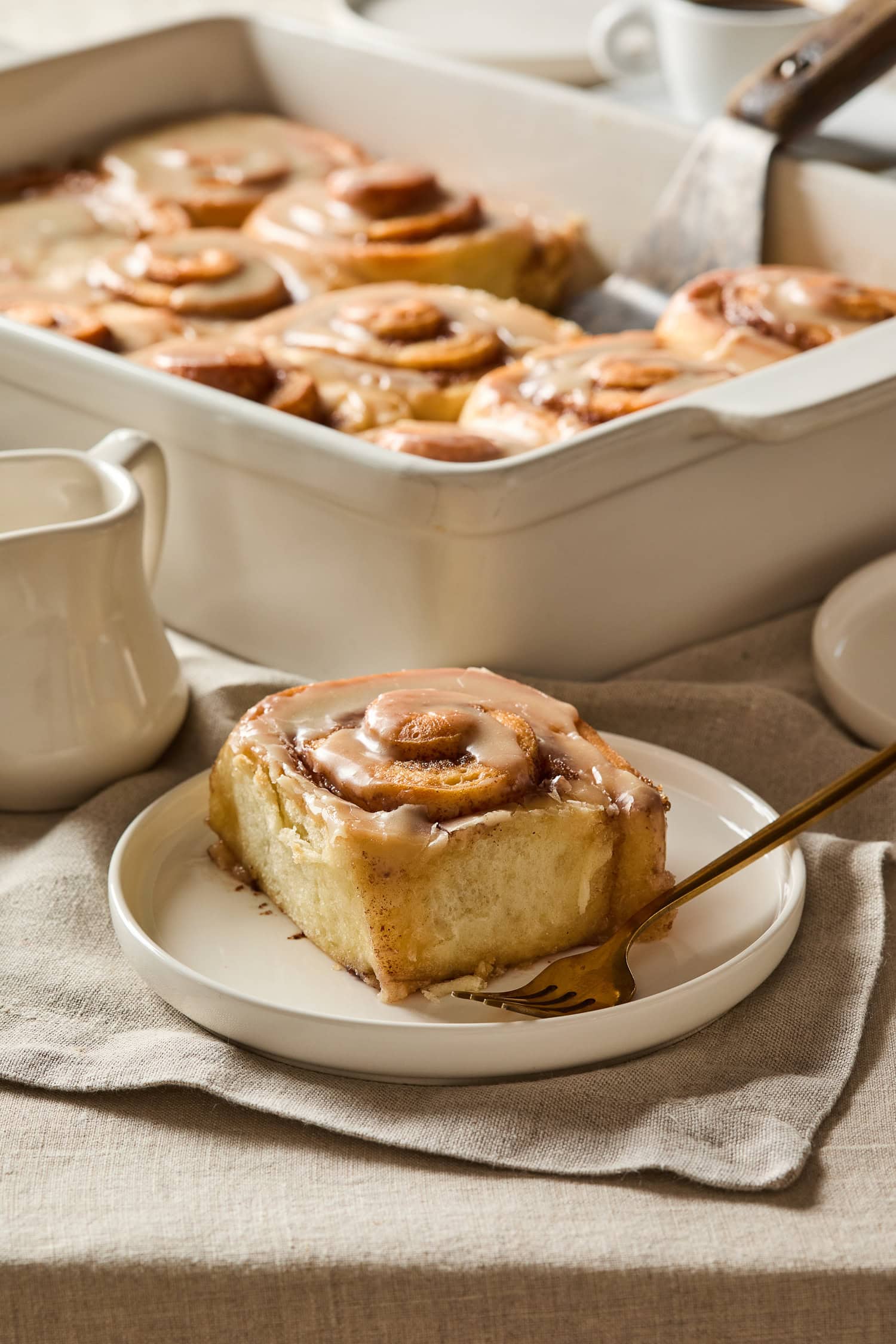 A cinnamon roll with brown butter icing on a plate.