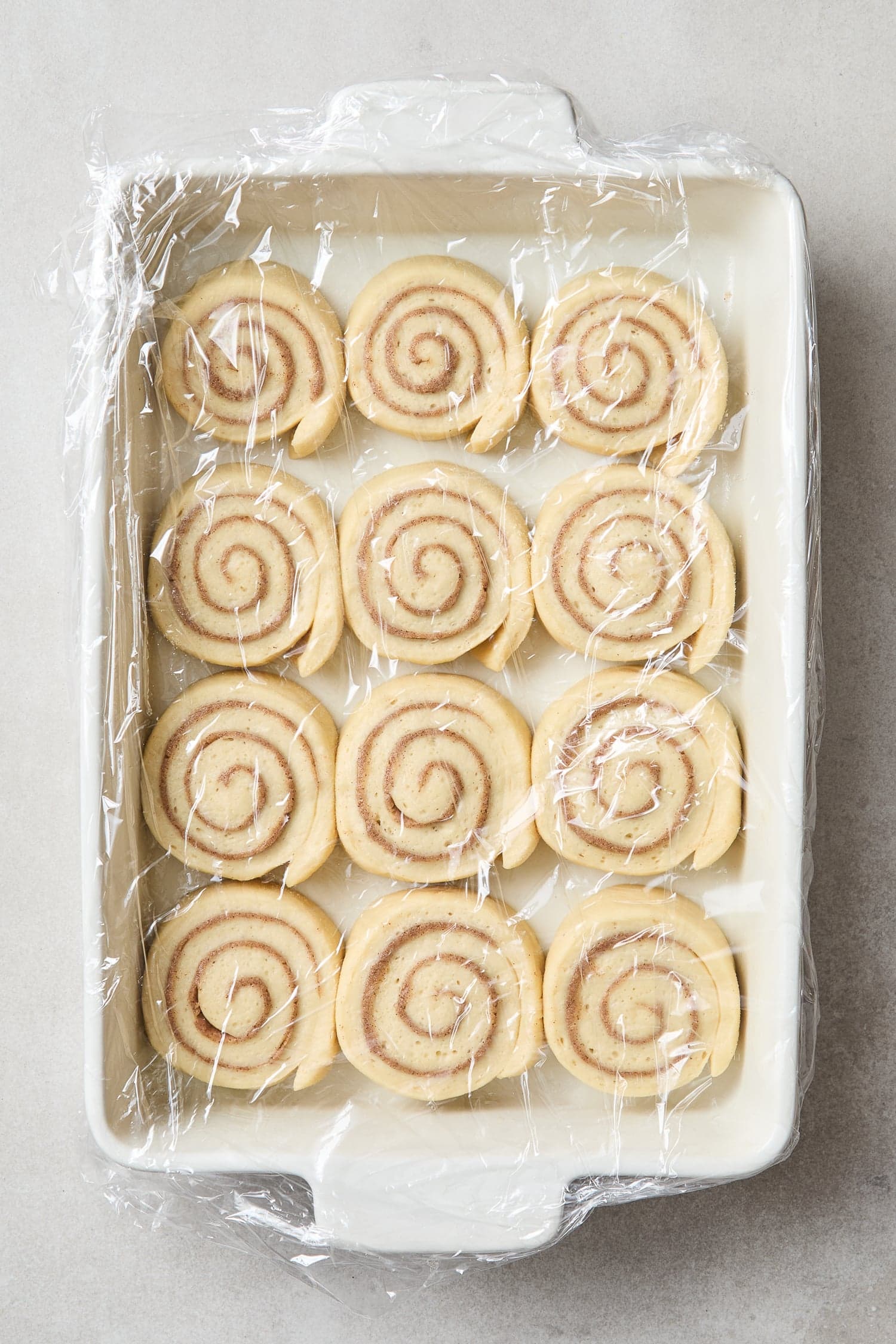 Sliced cinnamon rolls in a pan after rising.