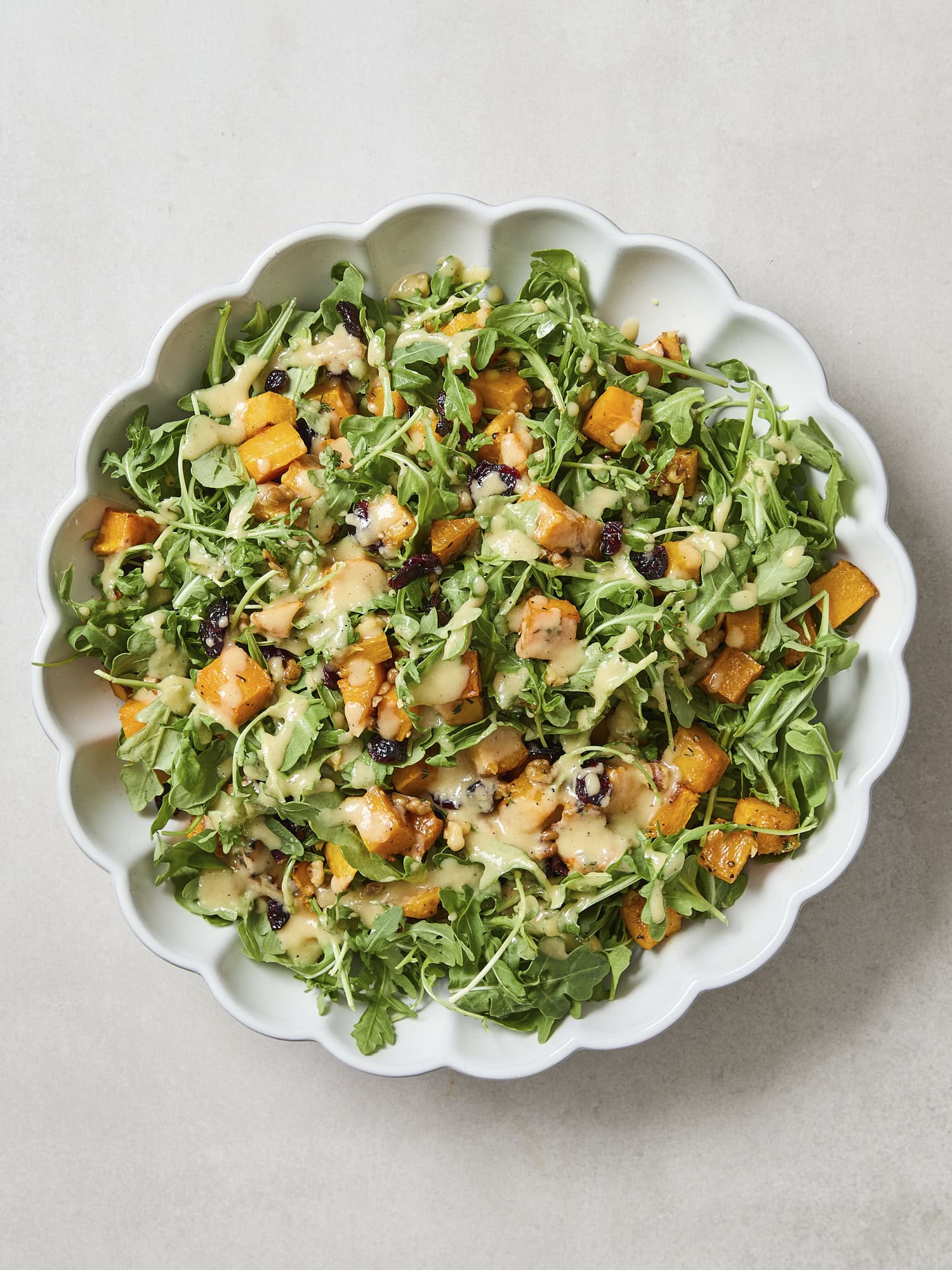 Roasted butternut squash salad drizzled with vinaigrette.