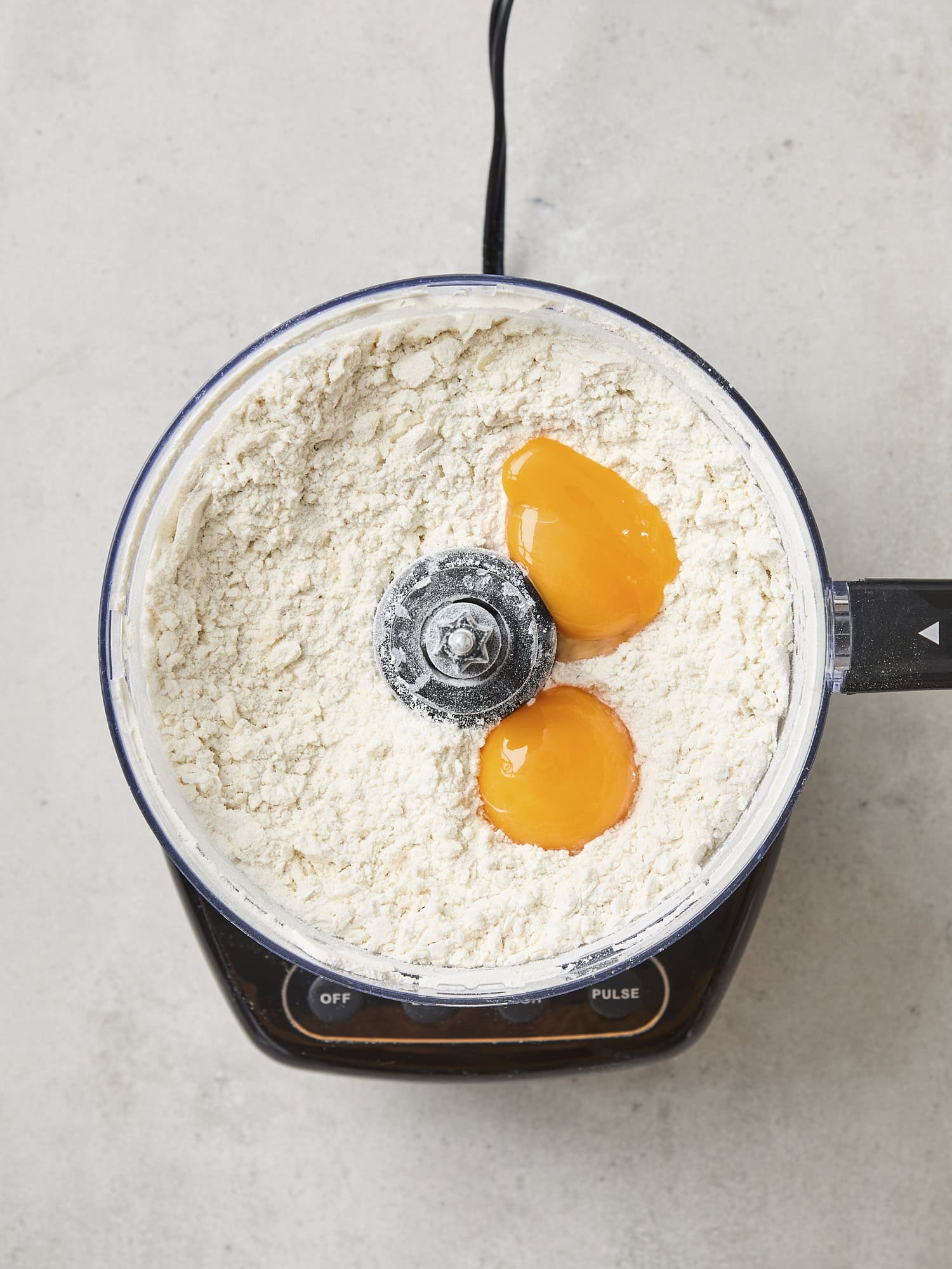 Egg yolks on top of dough in food processor.