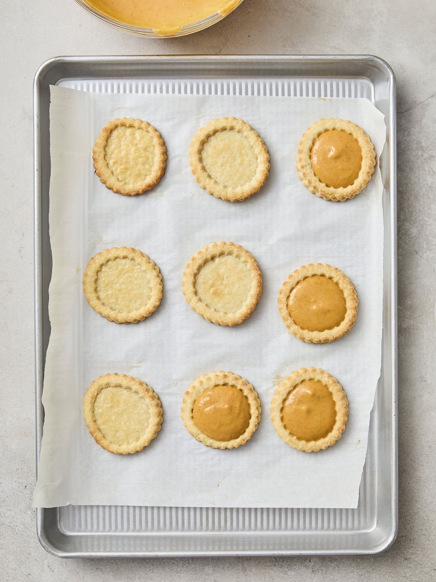Baked cookies being filled with pumpkin filling.